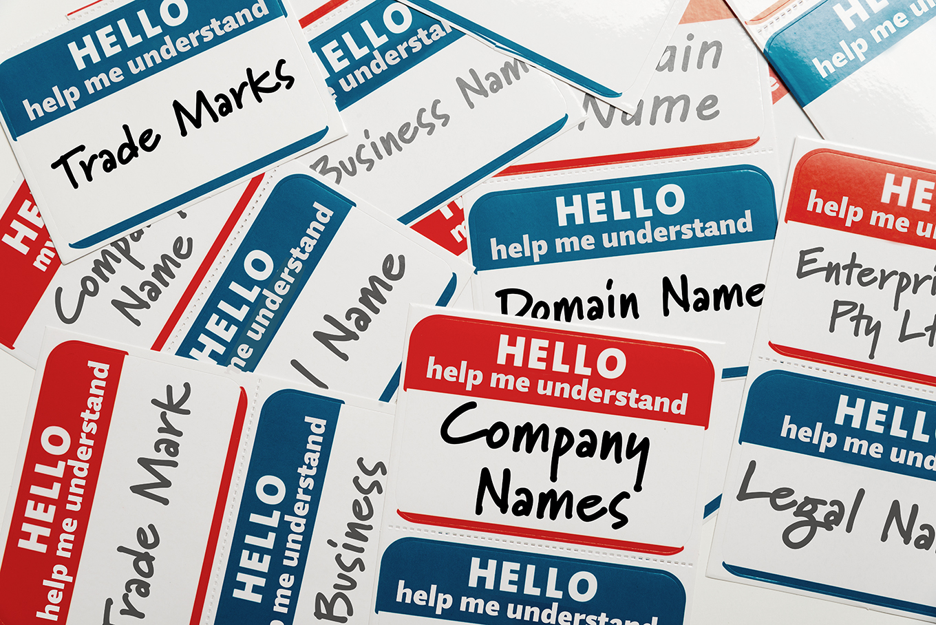 A stack of nametags with 'company names', 'trade marks', 'domain names' written in black marker.