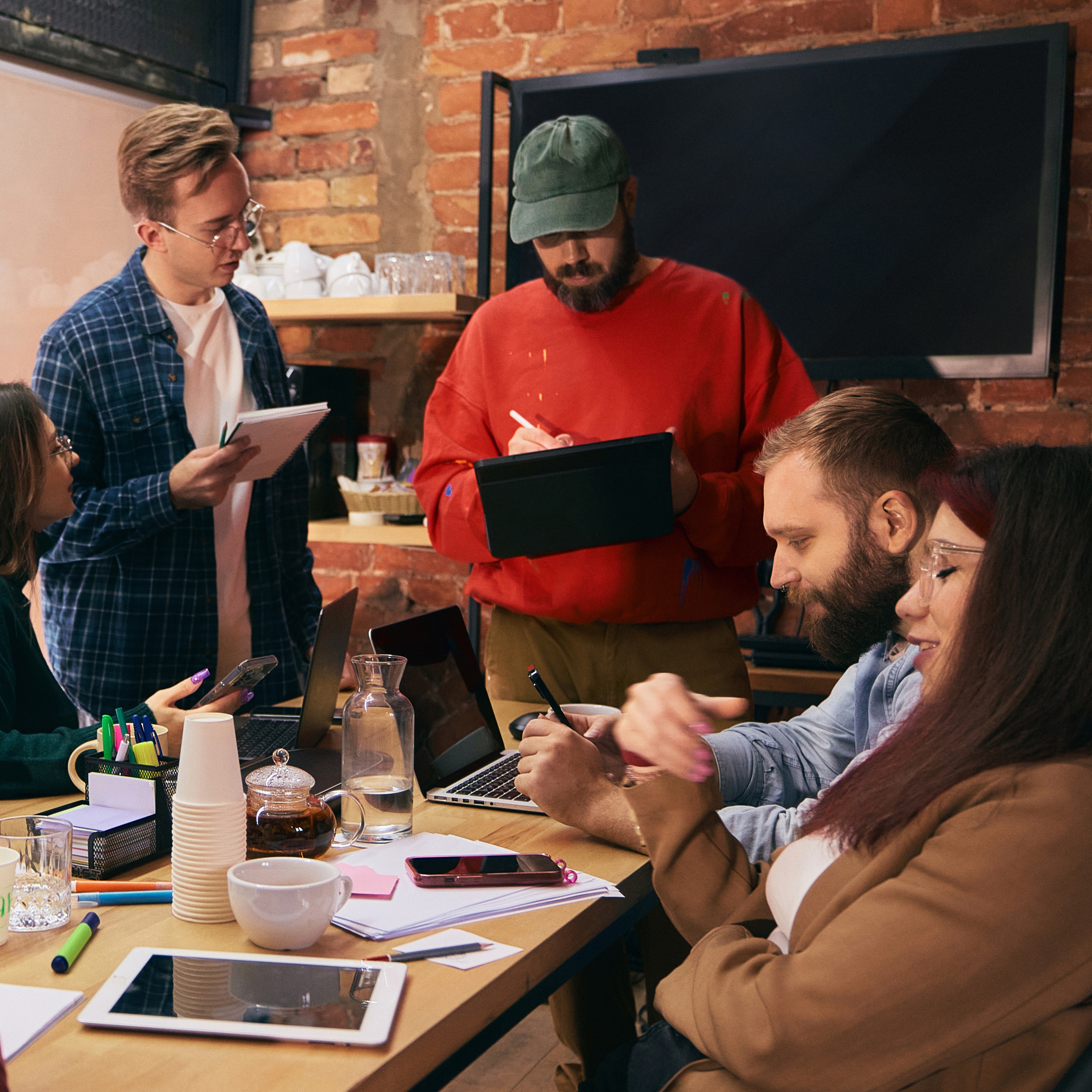 a group of people casually dressed around a table working to brainstorm names..